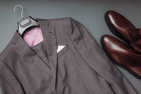 men's suit jacket on a hanger and chelsea boots for a wedding outfit